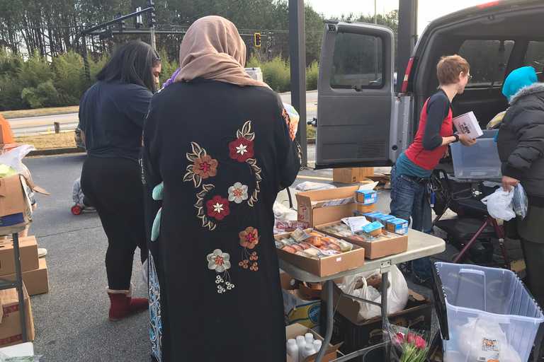Volunteers distributing donations on a table set up next to a car