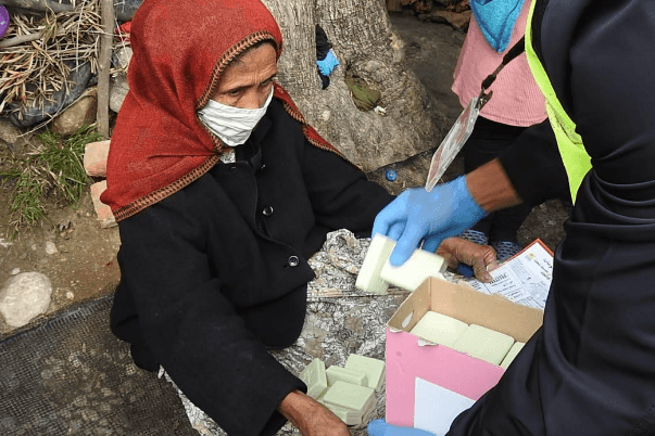 A woman receiving bars of soap from a volunteer handing them out