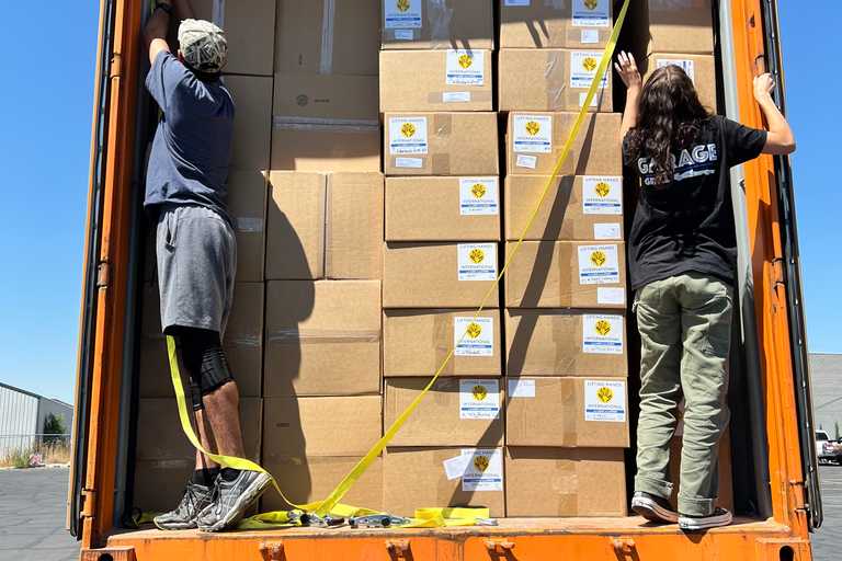 Volunteers loading boxes of aid items into a truck that is filled at full capacity
