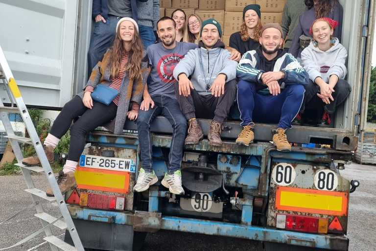 A group picture of volunteers posing inside a container full of boxes of aid donated to them
