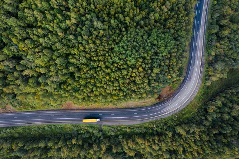 Aerial view of a truck driving on a road through a forest