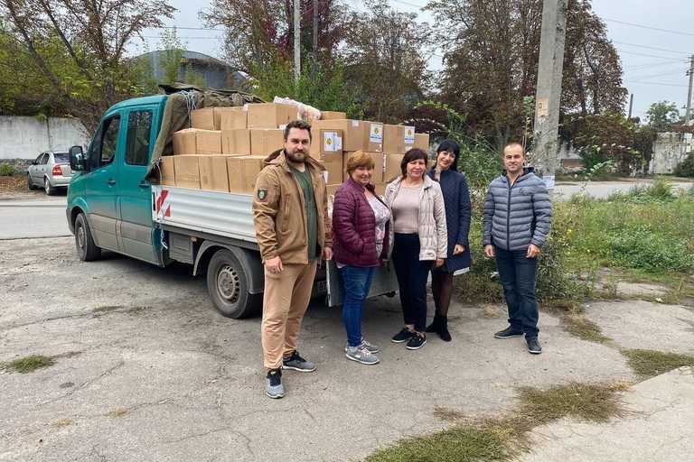Five people posing next to a truck full of boxes of donated aid items