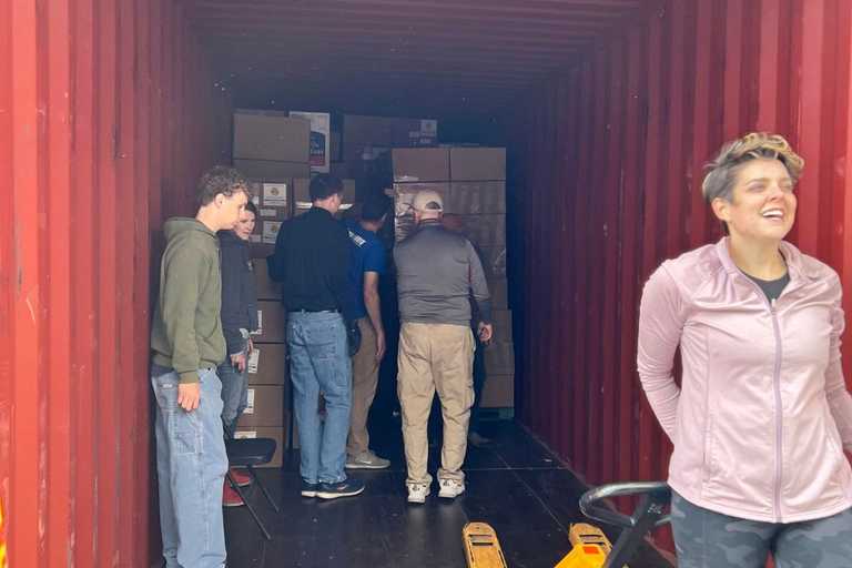 Volunteers loading a container full of boxes of donated items